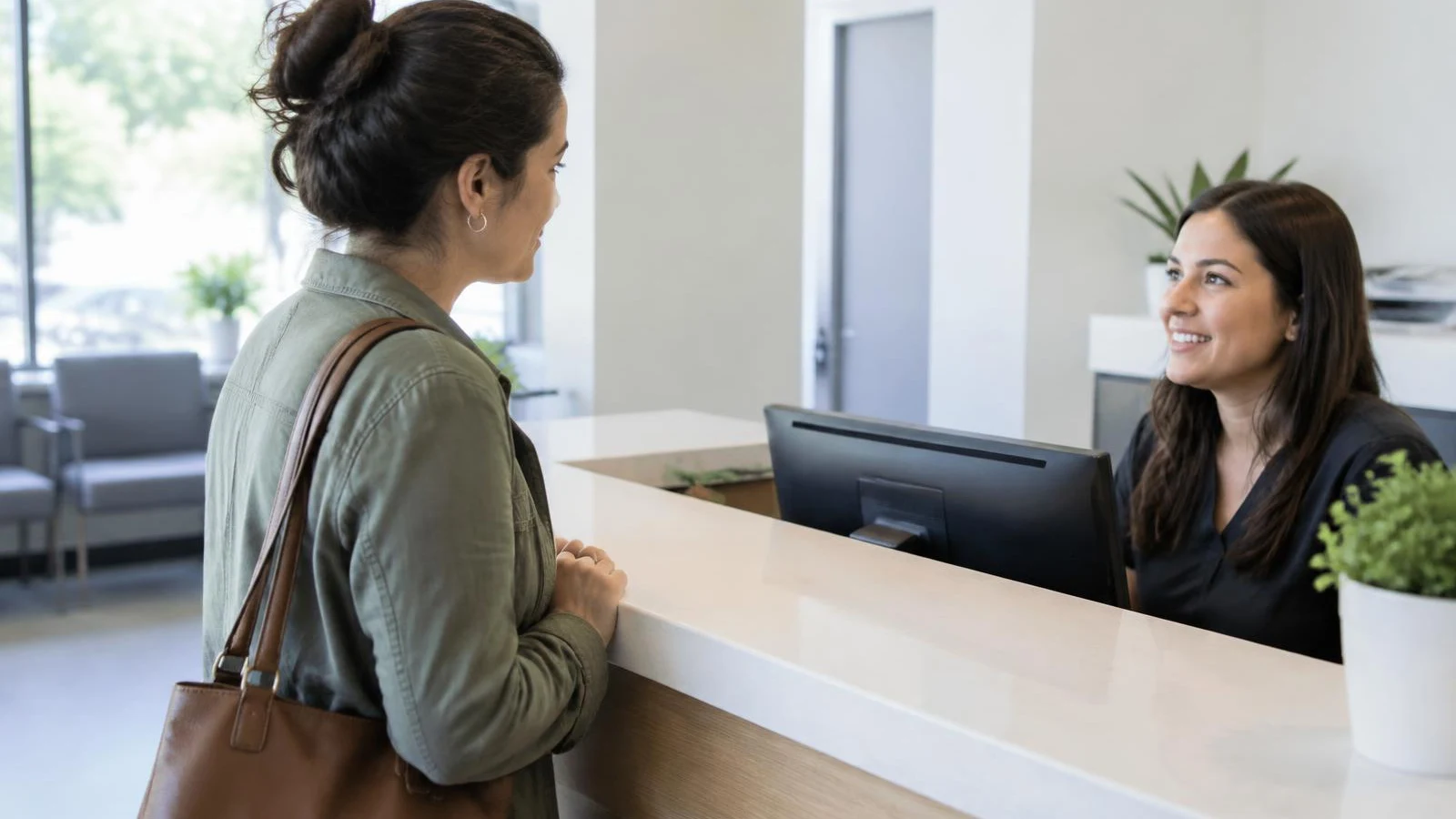 Patient checking in with a receptionist at a clinic front desk