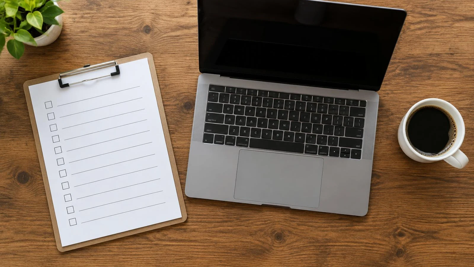 Clipboard checklist, laptop and coffee on a wooden desk